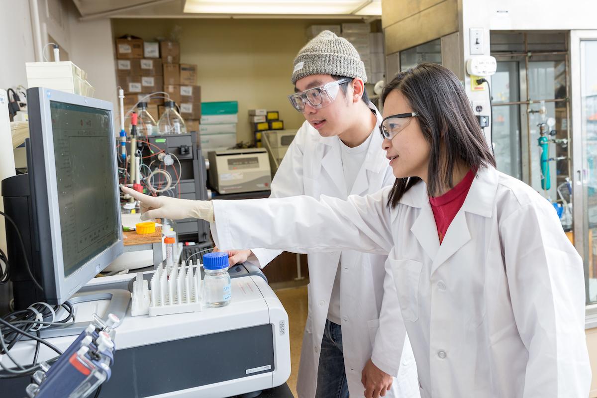 student and professor pointing in a lab